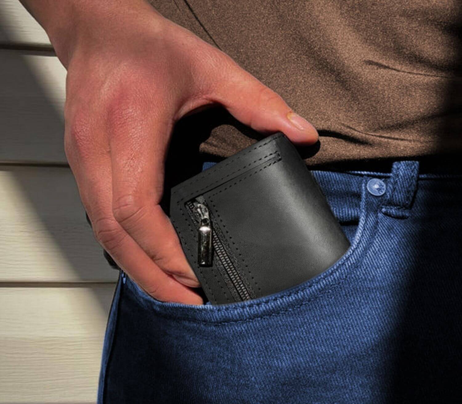 Black men’s slim leather wallet with zipper pocket being placed into front jeans pocket for everyday carry