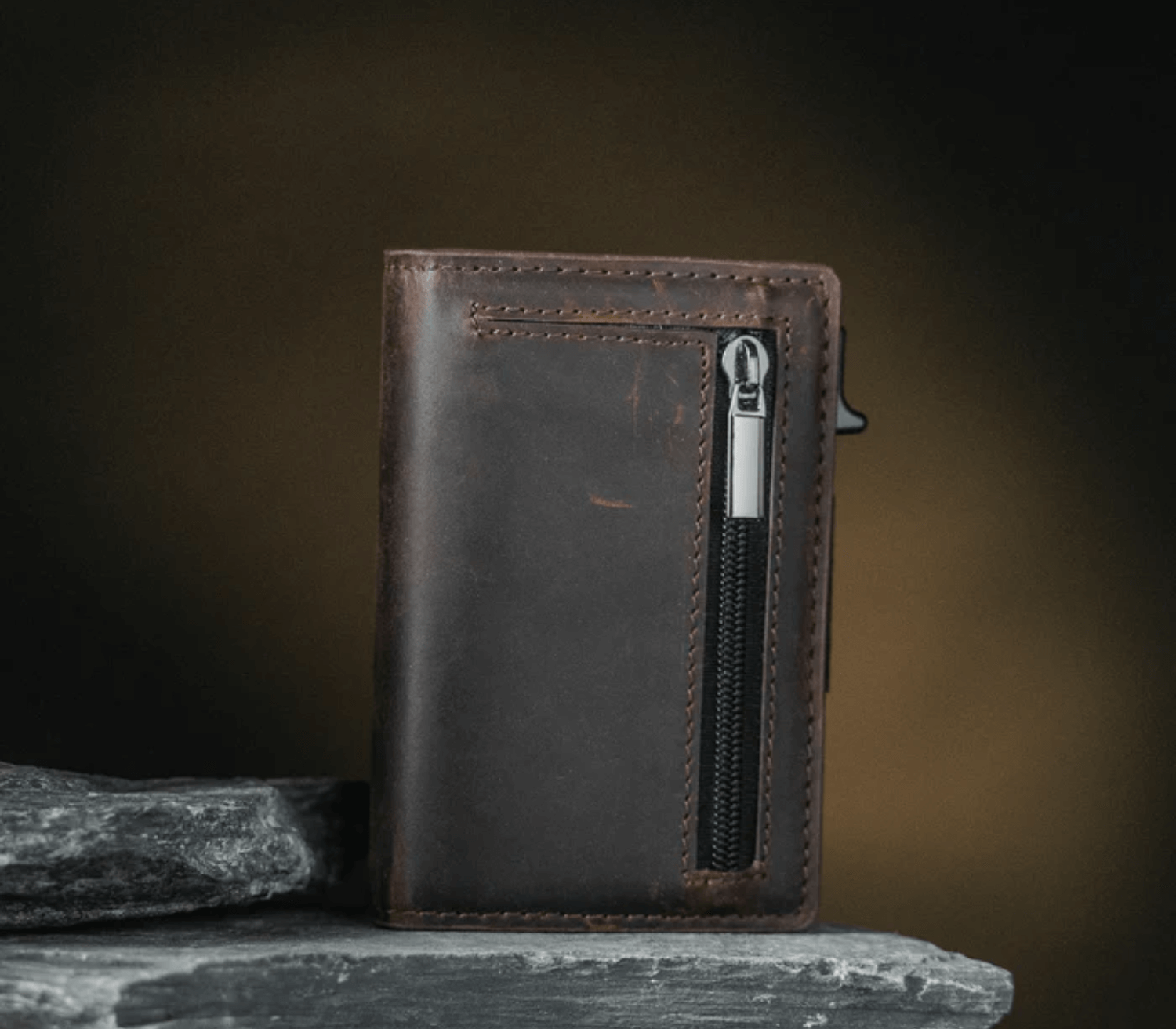 Brown men’s leather wallet with zipper pocket displayed on stone surface in a rugged, durable style